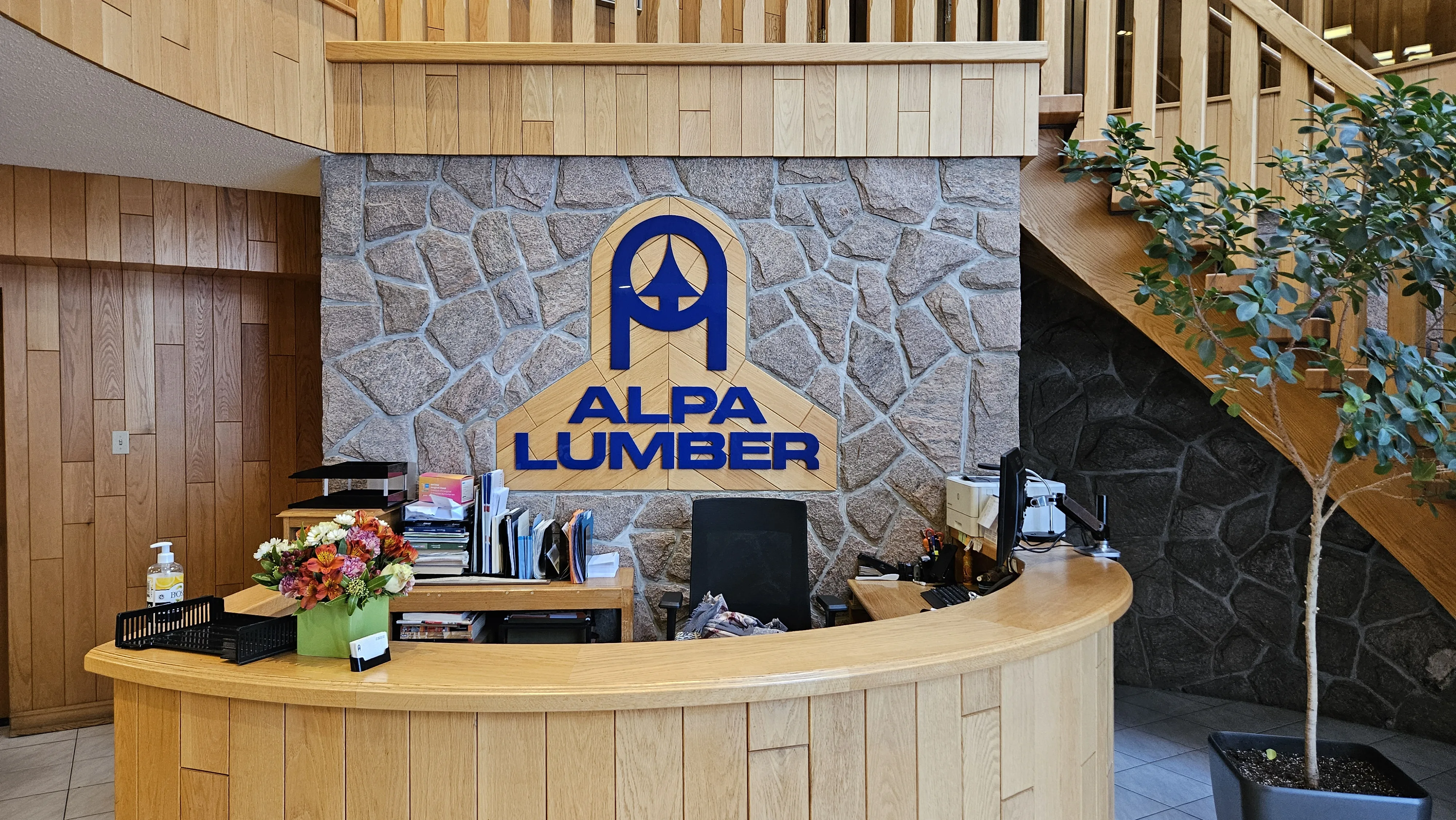Alpa Lumber reception with logo on stone wall