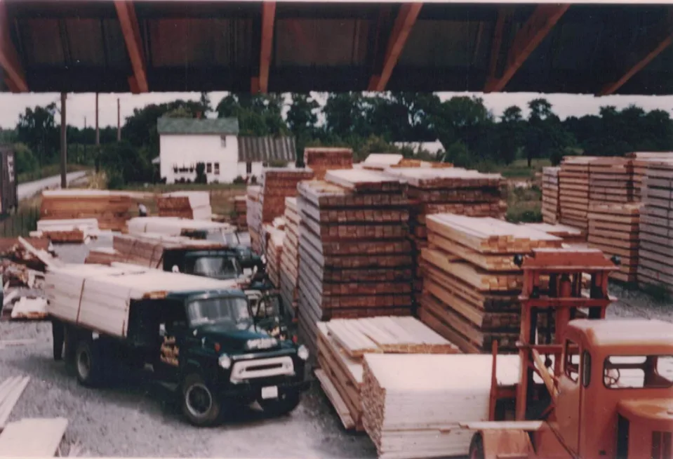Vintage Alpa Lumber yard with stacked timber and a delivery truck